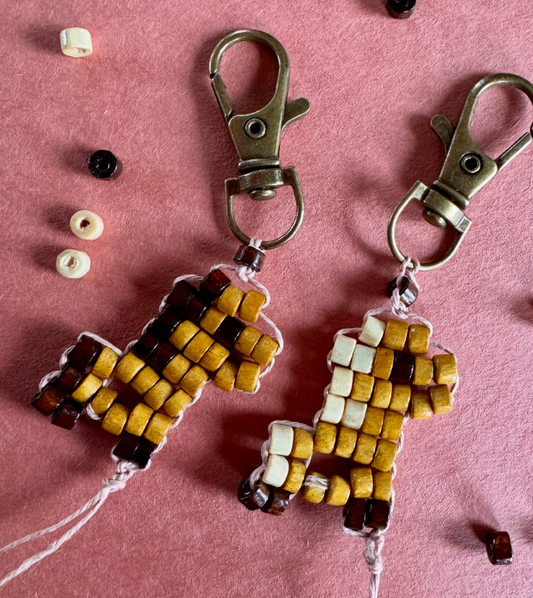 Two tiny keychains in the shape of ponies made from small wooden beads, hemp cord and brass lobster clasps